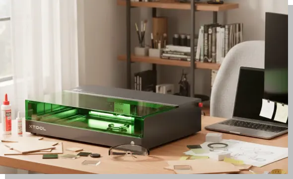 自宅のデスク上に設置されたコンパクトなレーザーカッター。自室を工房に変え、省スペースでモノづくりを行っている制作環境のイメージ。
