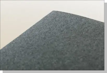 細目（#320〜#400程度）のサンディングペーパーの表面拡大写真。粒子が非常に細かく、一見すると滑らかなグレーの面に見えるほど繊細な質感のイメージ。